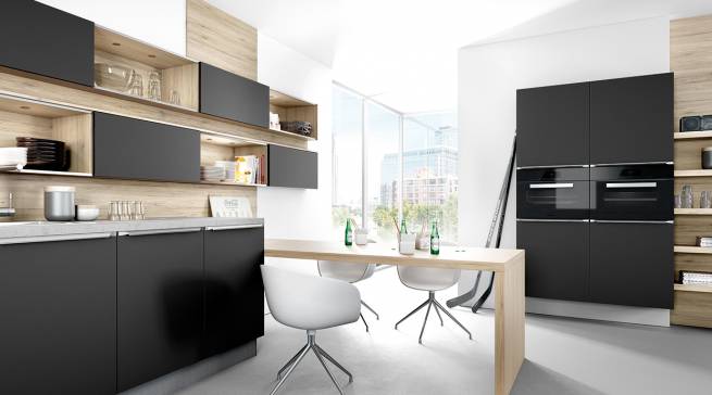Mattlack in Schwarz, kombiniert mit warmem Holz, setzt in der Küche auffallende Akzente. Absolut im Trend: hoch eingebaute Hausgeräte. Foto: AMK
