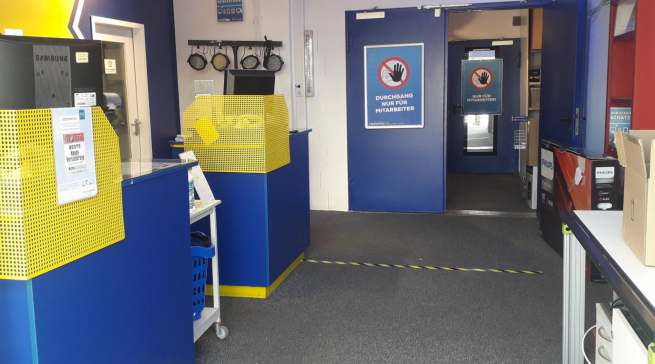 Schwarz-gelbe Bodenmarkierungen sollen den Abstand der Kunden zueinander gewährleisten. Das klappte bei unserem Kurzbesuch problemlos.