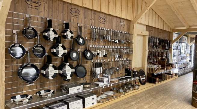 Die Optik der Rösle Grillhütte wurde auf das Grilldorado übertragen: Mit halbhohen Trennwänden und Regalen aus Holzbalken. Rösle selbst ist mit Grillgeräten und Zubehör vertreten.