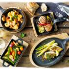 Für die Garnelen, das Gemüse oder den Fisch: In den gusseisernen Pfannen von Küchenprofi lassen sich die Köstlichkeiten zubereiten und servieren. Dann kommt der Untersetzer aus Pinienholz zum Einsatz.