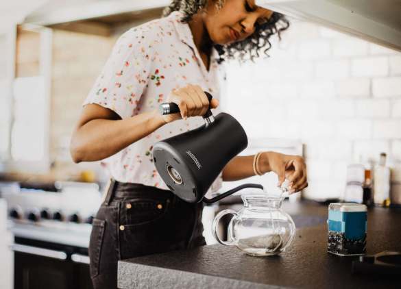 A black woman pours tea in her kitchen