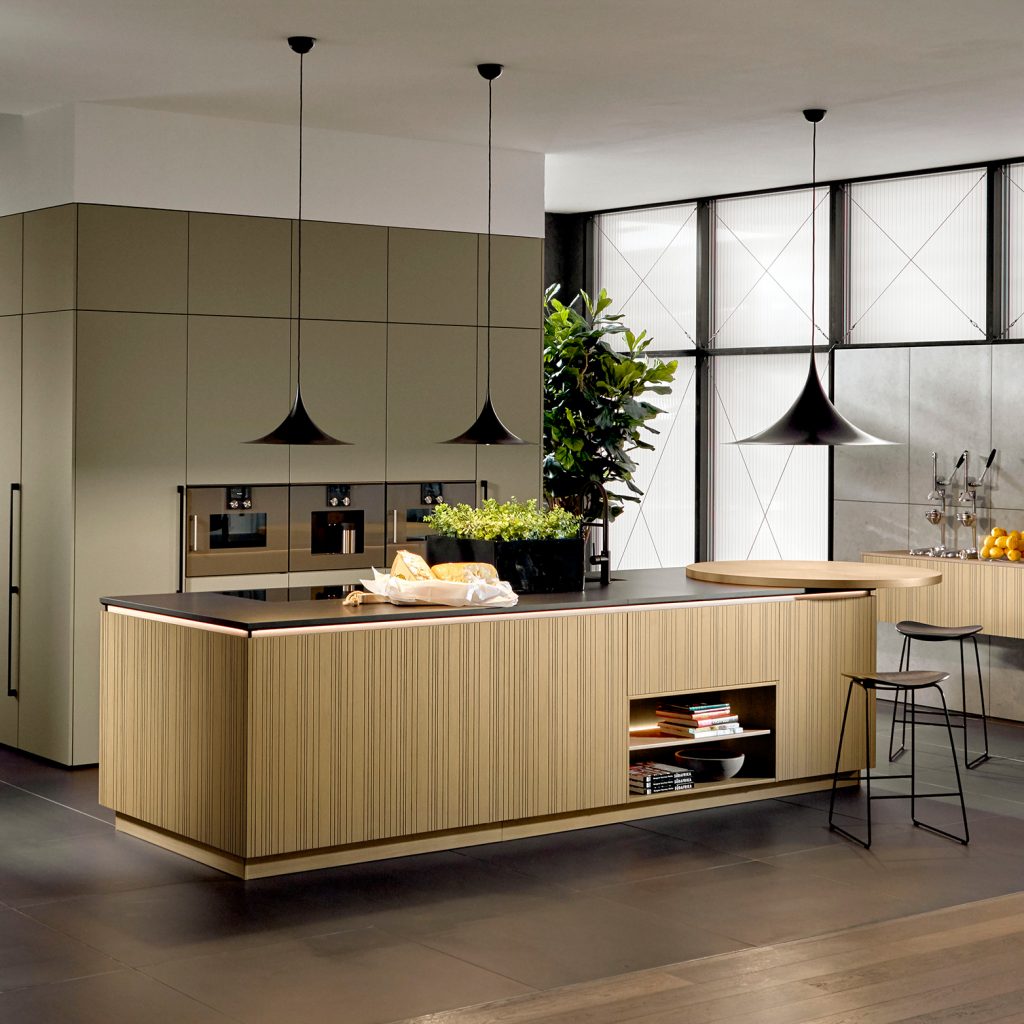 Modern, stilvoll, exklusiv mutet diese grifflose Wohnküche an. Der Kaffeevollautomat zwischen zwei weiteren Luxus-Einbaugeräten lädt zum Experimentieren und zum anschließenden Genießen an der runden Esstheke ein. (Foto: AMK)