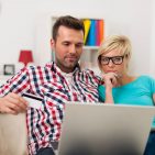 Couple sitting on sofa at home and paying bill on line