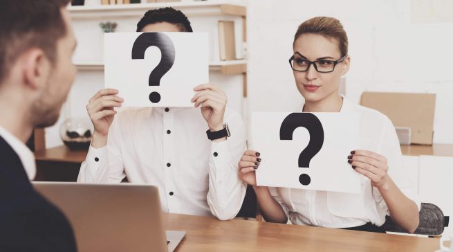Coworkers are holding question marks at job interview.