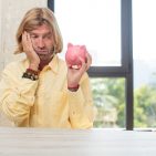 young adult caucasian man feeling bored, frustrated and sleepy after a tiresome. piggy bank concept