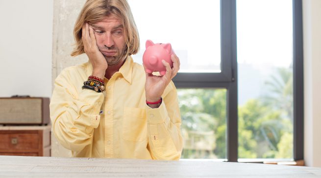 young adult caucasian man feeling bored, frustrated and sleepy after a tiresome. piggy bank concept