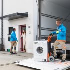 Coolblue erweitert seine Logistikinfrastruktur: Ein Lieferteam bringt eine Waschmaschine im firmeneigenen Transporter direkt zum Kunden – ab sofort auch im Großraum Berlin mit Next-Day-Service und Installation.