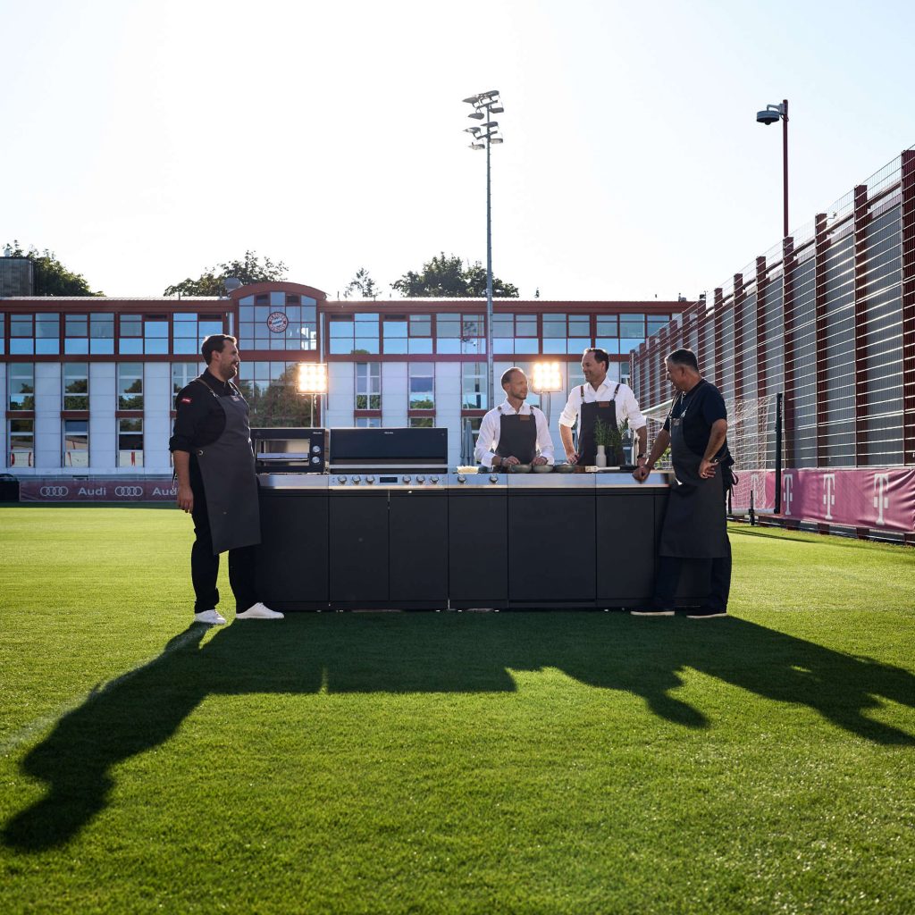 Kochen verbindet: Dr. Axel Kniehl (2. v. r.), Rouven Kasper (2.
v. l.), Spitzenkoch Julian Resch (l.) und FC Bayern Legende Roy
Makaay (r.) zusammen mit der neuen Miele Outdoor-Küche auf dem
FC Bayern Trainingsgelände.