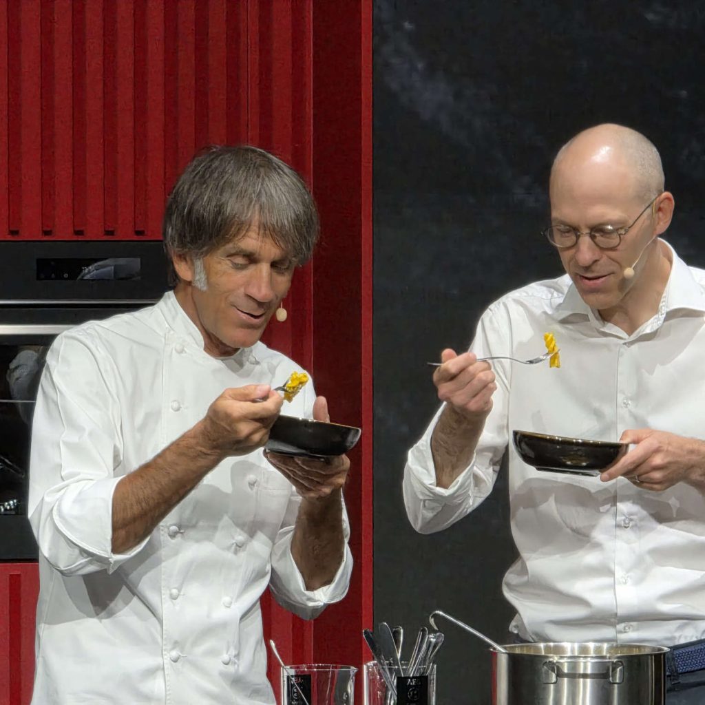 Der zweifache Sternekoch Davide Oldani (l.) und Leandro Jasiocha (r.), CEO / Head of Region EMEA der Electrolux Group, lassen sich sichtlich begeistert die Nudel schmecken, die auf dem ersten Kochfeld von AEG mit speziell entwickelter OnePot Pasta-Funktion perfekt zubereitet wurde. Foto: G. Wagner